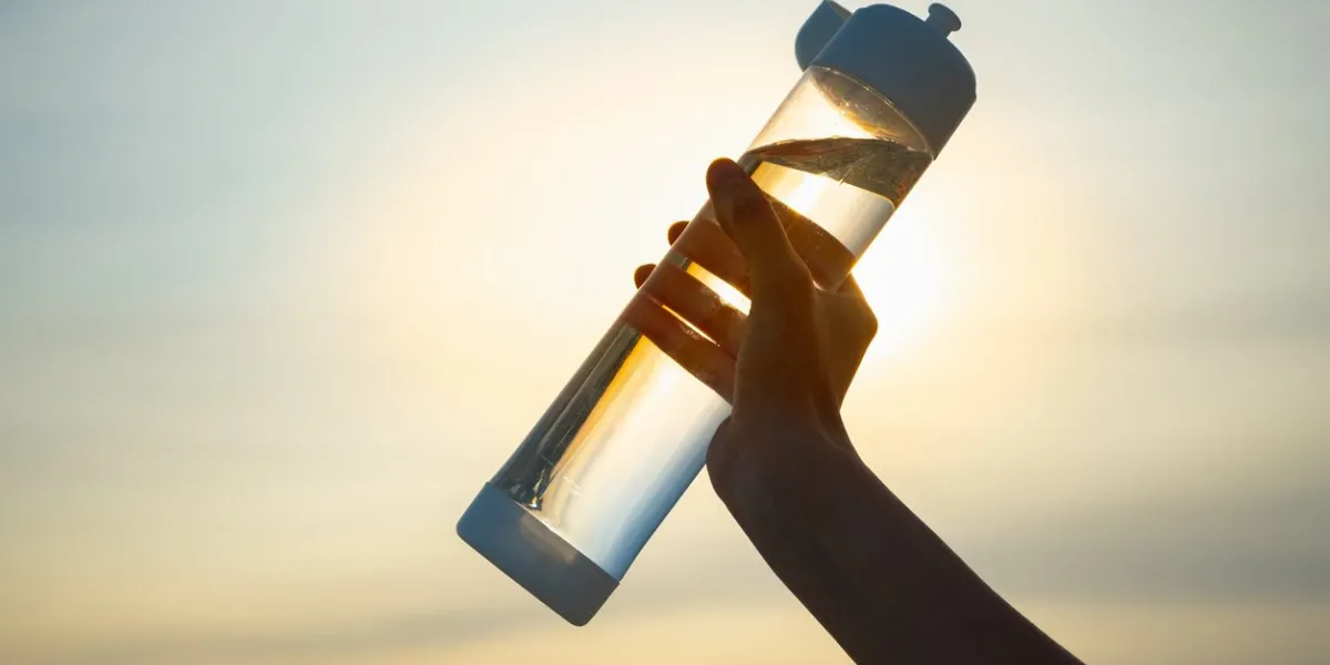 close up of a reusable water bottle in a human hand, concept of thirst, rehydration and decreasing single use plastic