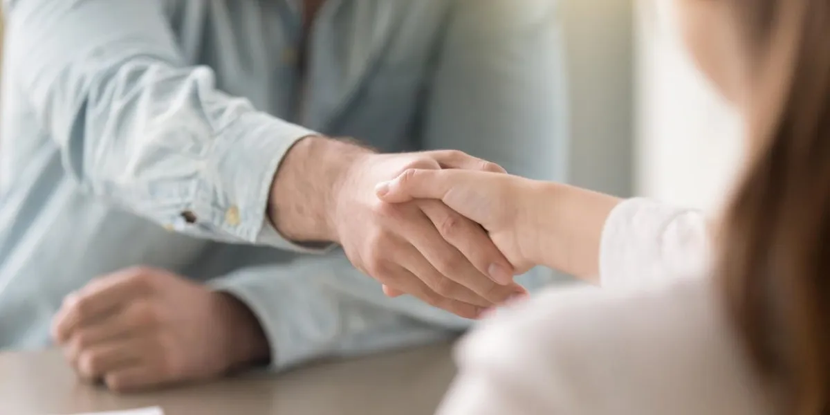 businessman shaking female hand above the table business agreement and partnership concept partners closing a deal, view over the shoulder formal greeting gesture, effective negotiations