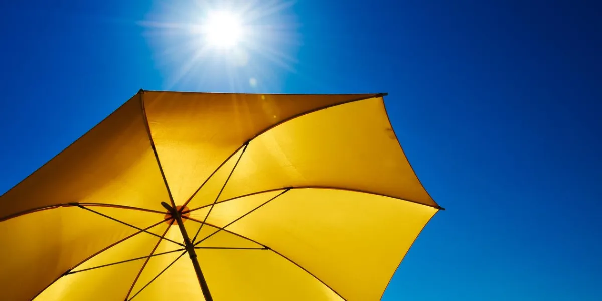 yellow umbrella with bright sun and blue sky