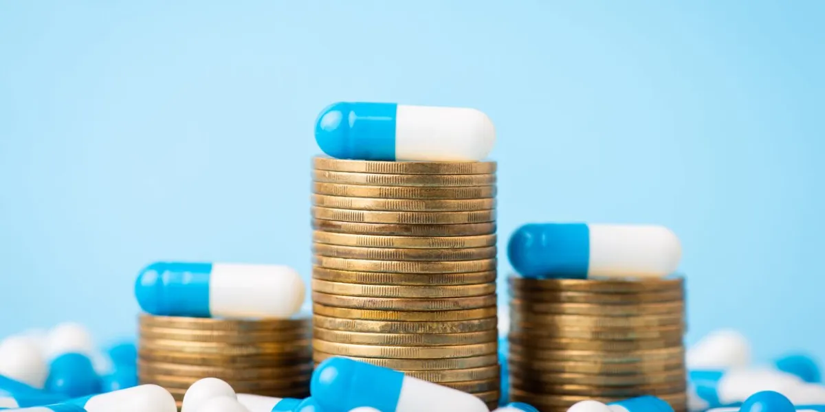 stacks of coins between medical pills capsules