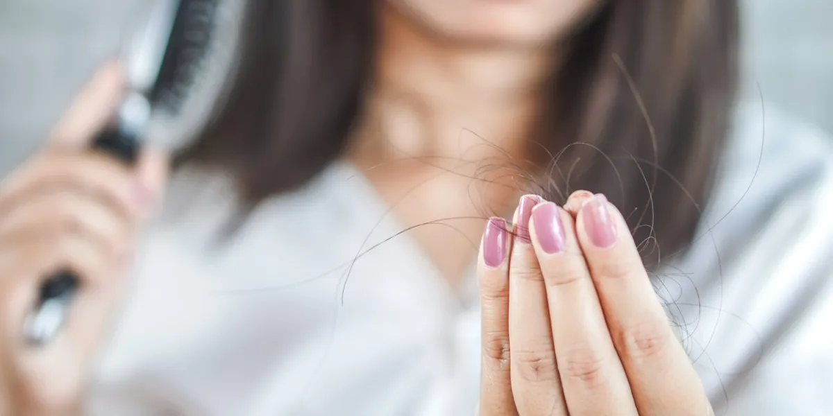 closeup woman hand holding hair fall from hairbrush