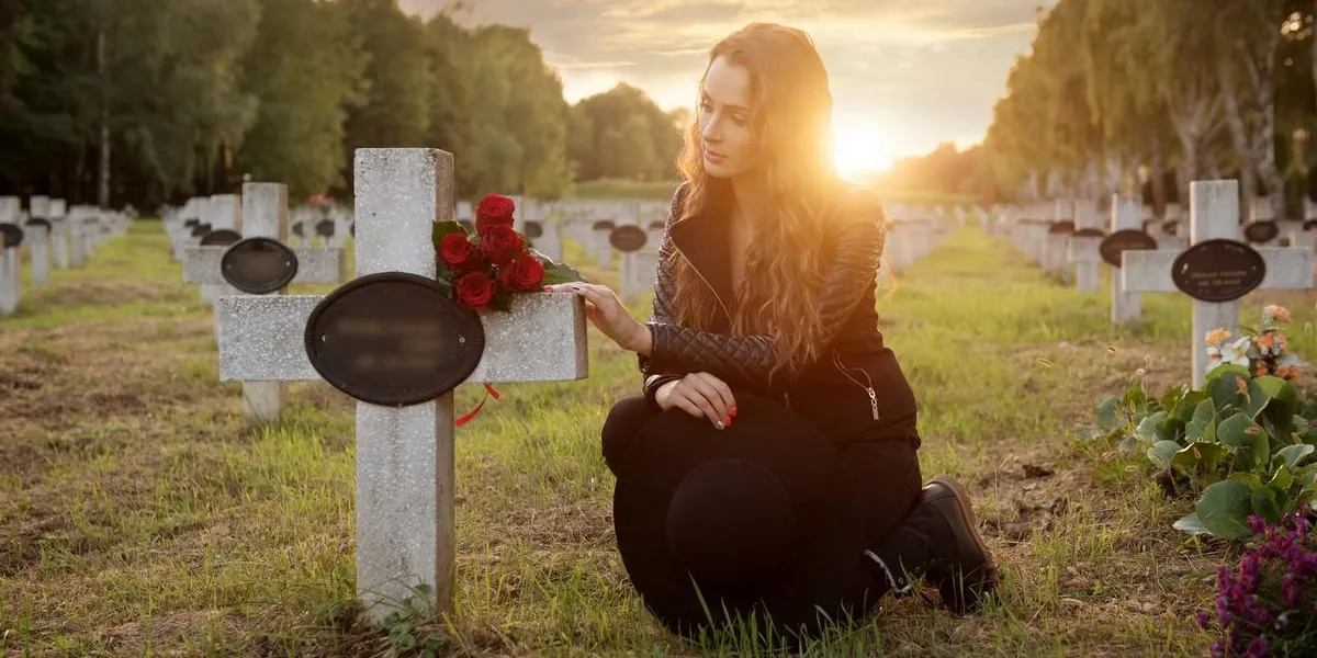 sad woman in the cemetery, holding a bouquet of roses in her hand