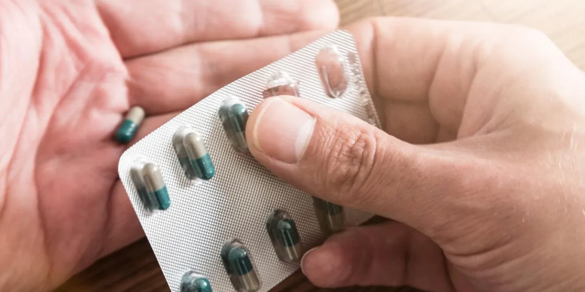 male hands removing pills from foil blister pack
