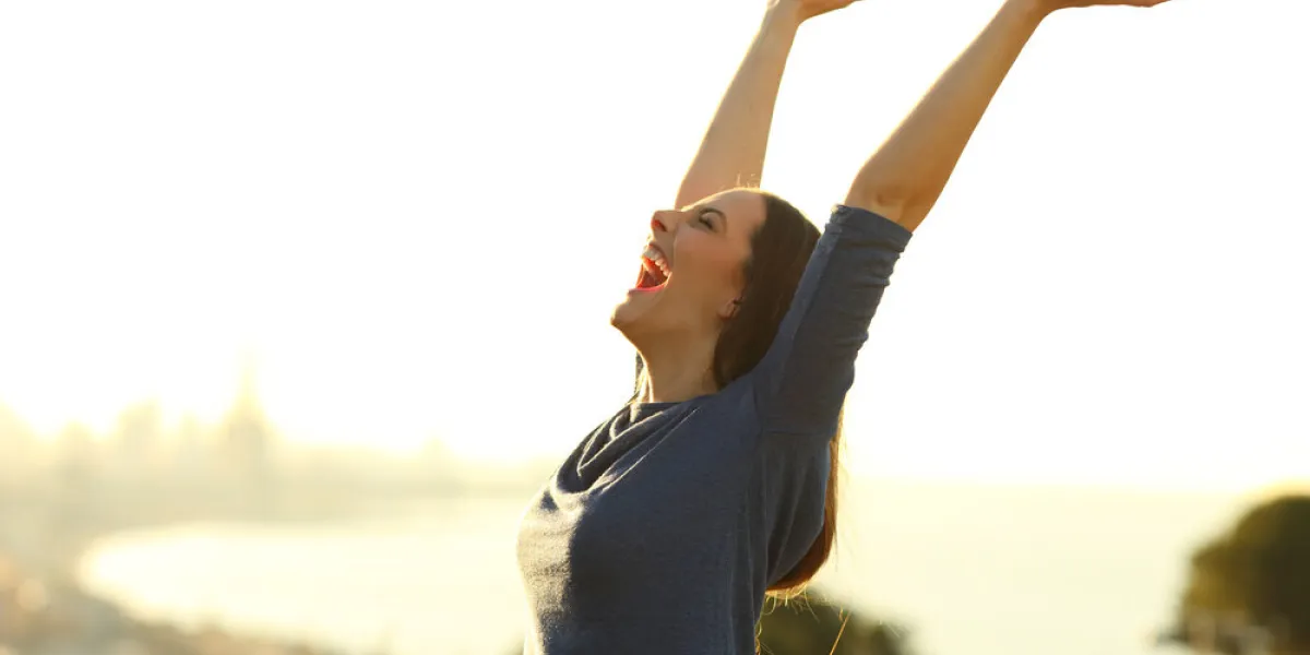 excited woman screaming with arms up outdoors