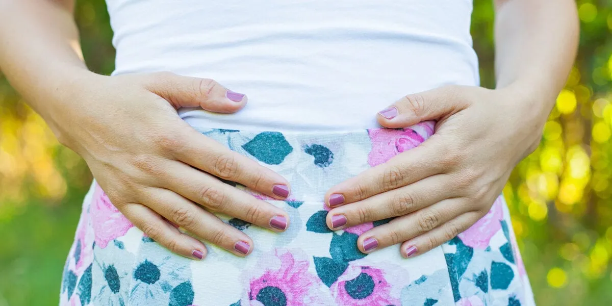 close up picture of happy pregnant woman holding her tummy, posing outdoor