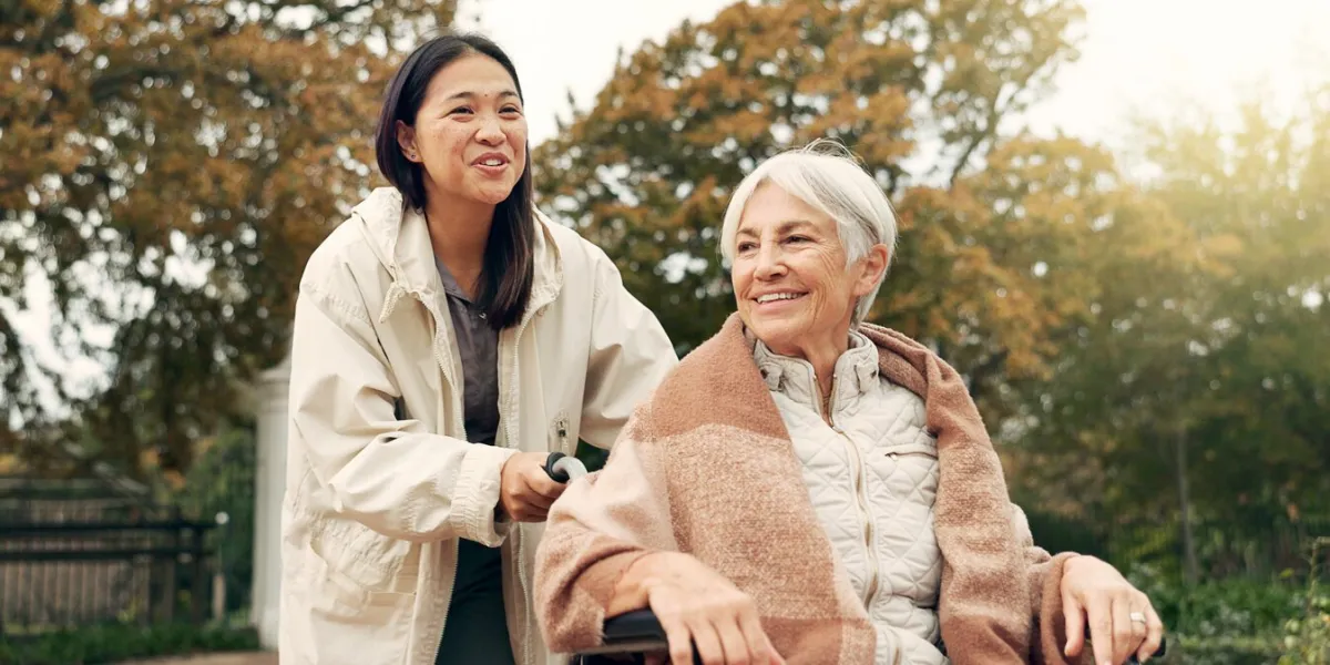 elderly woman, wheelchair and nurse in park, nature or garden outdoor happy, senior person with a disability and walking with caregiver for health, wellness and physical therapy for rehabilitation