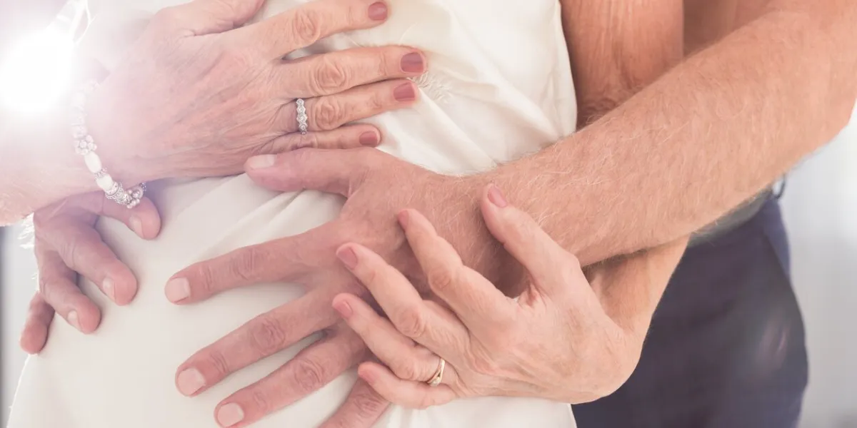 cropped shot of a man's hands caressing his wife's body