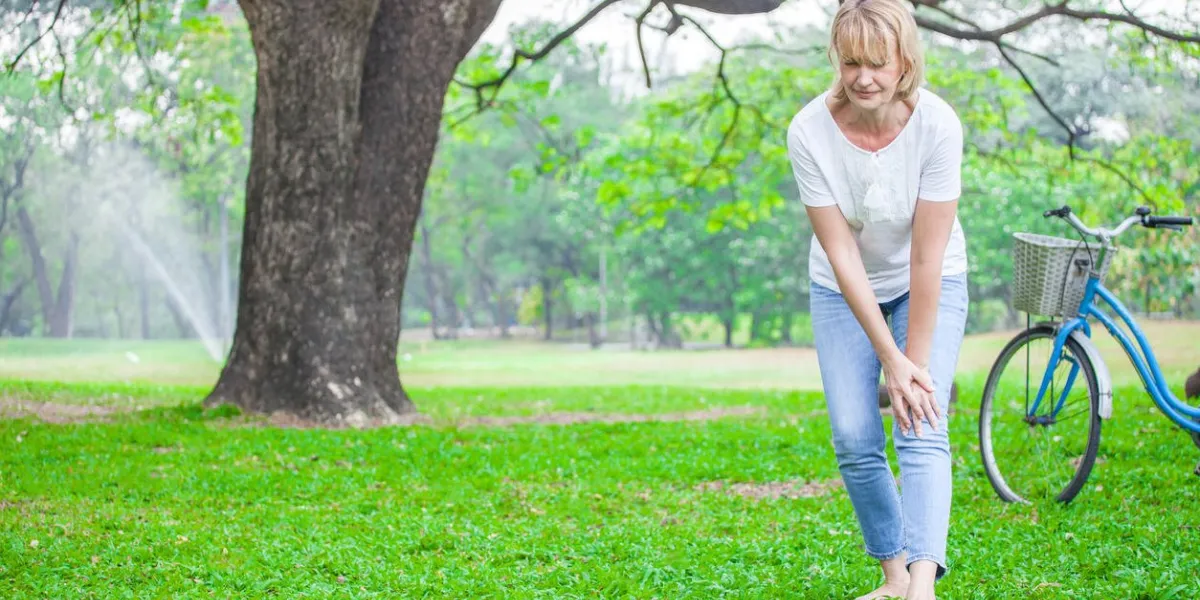 senior woman walking in autumn park and having knee pain arthritis pain concept
