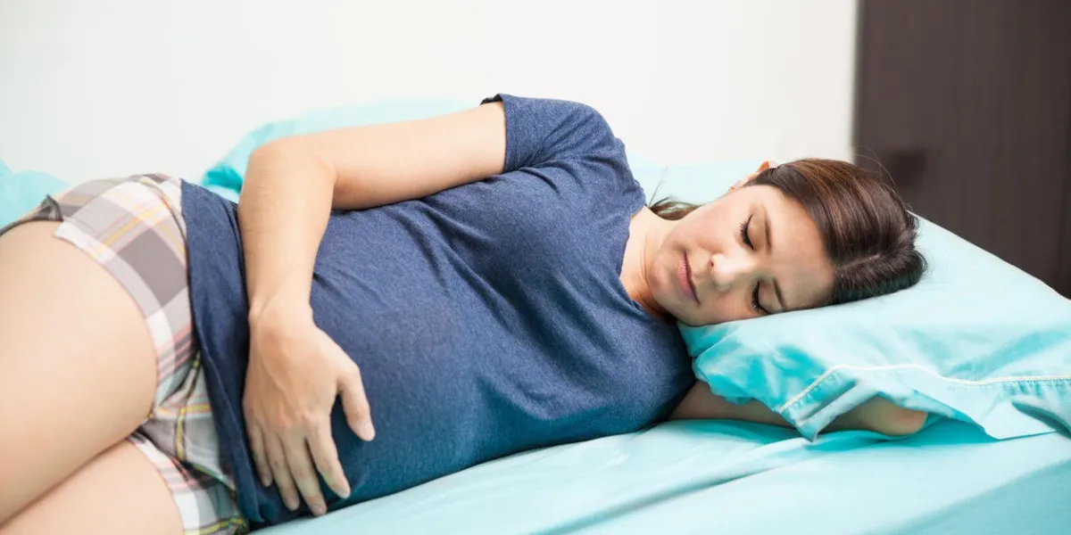 jolie jeune femme enceinte allongée sur un lit et dormir un peu sur son côté droit
