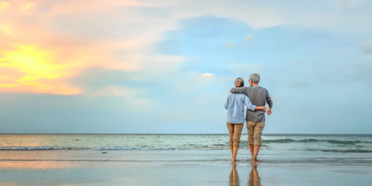 plan life insurance of happy retirement concepts senior couple walking on the beach holding hands at beach sunrise in evening