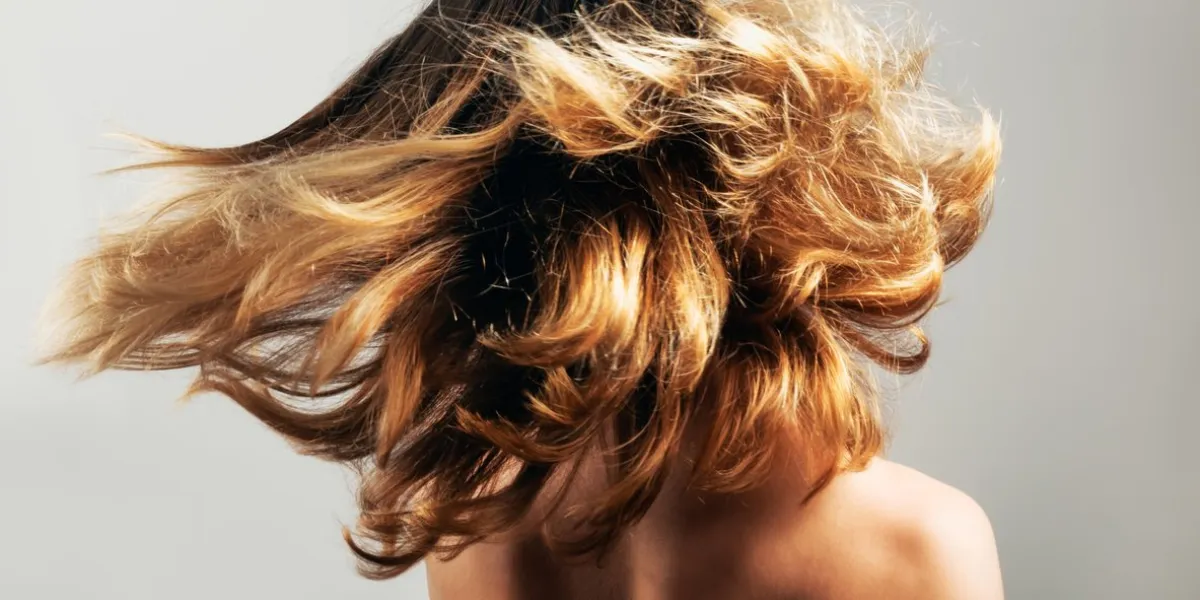 young woman tossing her beautiful healthy thick hair concept of youth, freedom wellbeing, craziness and good health