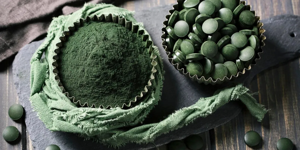 comprimés de spiruline et de la poudre dans des bols sur un fond en bois