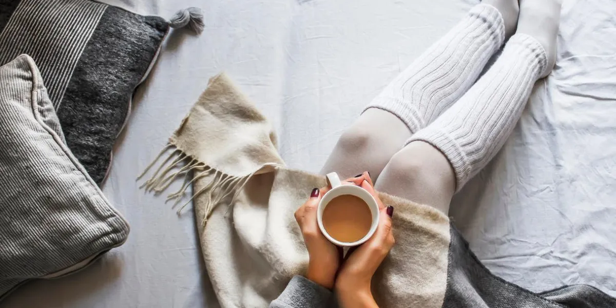 jeune femme assise sur une mauvaise tenue une tasse de café chaud sur un froid matin d'hiver à la maison