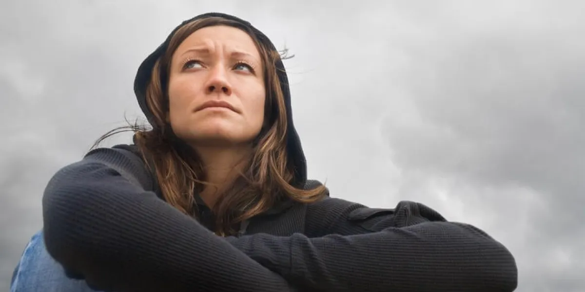fille assise et contemplant sur un fond de ciel nuageux