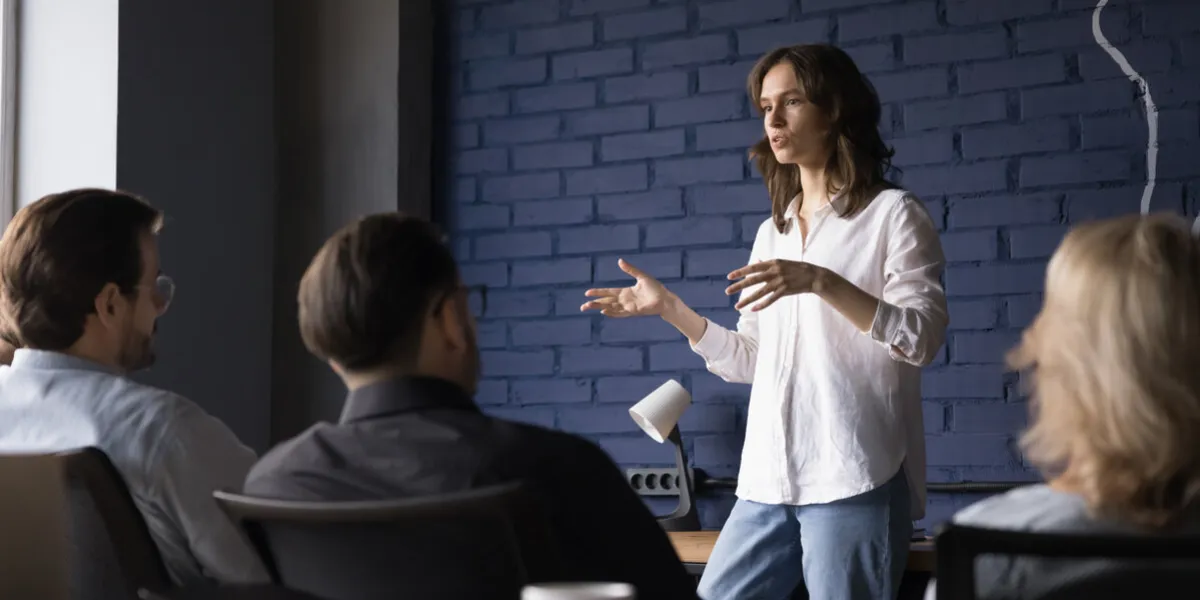 engaged confident business project female leader talking to team, telling strategy, plan, presenting tasks serious pretty presenter girl speaking to coworkers, brainstorming on meeting