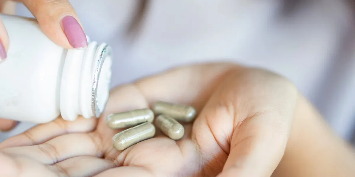closeup woman hand taking herb medicine tablets