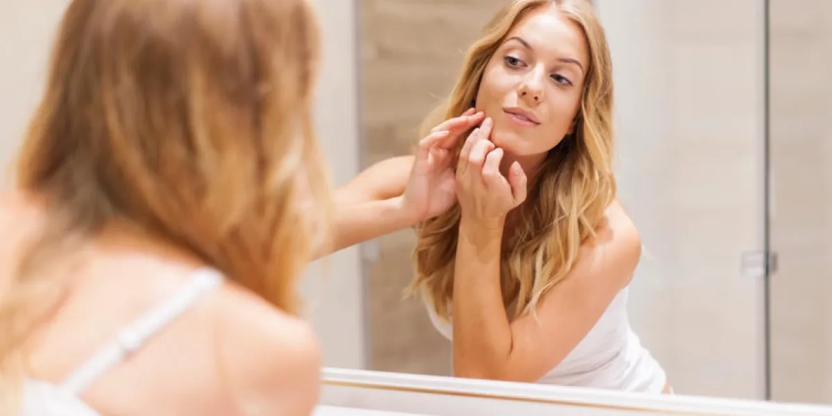 femme blonde a des problèmes avec la peau sur le visage