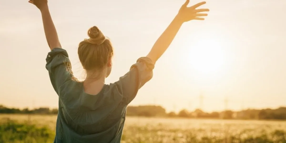 female teen girl stand feel freedom with arms stretched to the sky, sunset light