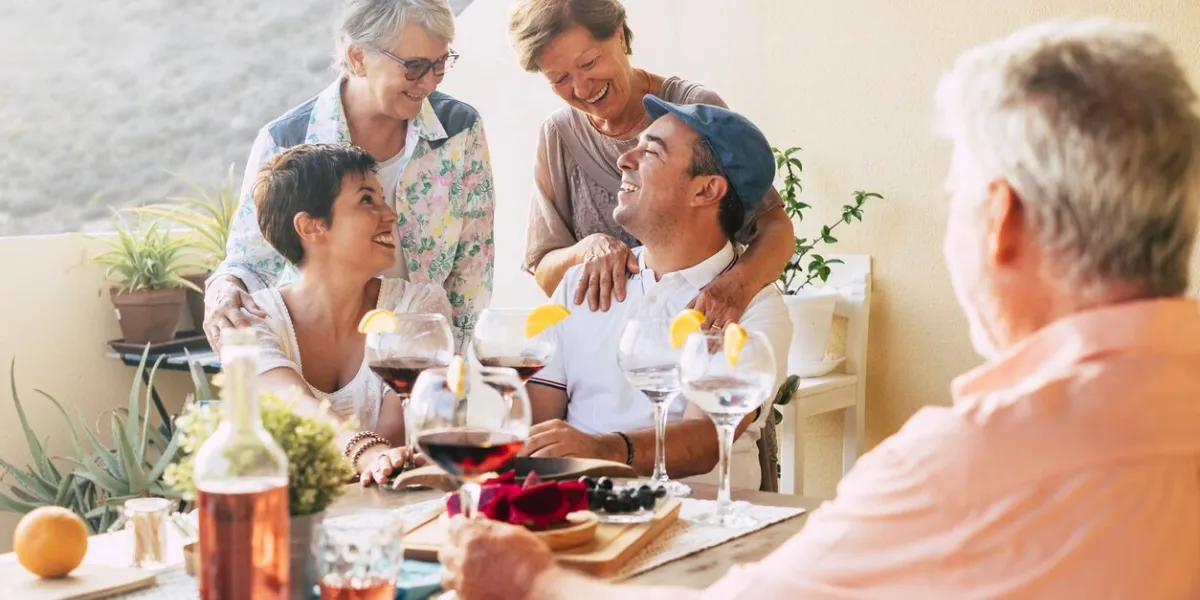 happy group of friends outdoor celebrating and having fun together during a dinner in the terrace at home laughs and smiles in friendship for mixed ages people