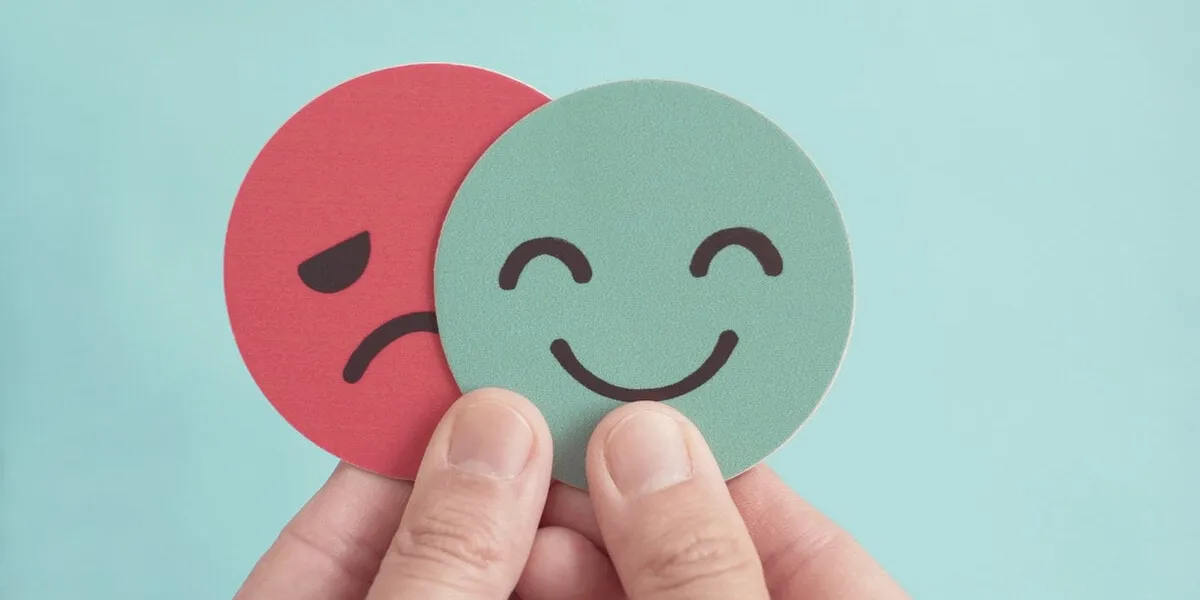 hands holding sad face hiding behind happy face, bipolar and depression, mental health, split personality, mood change concept