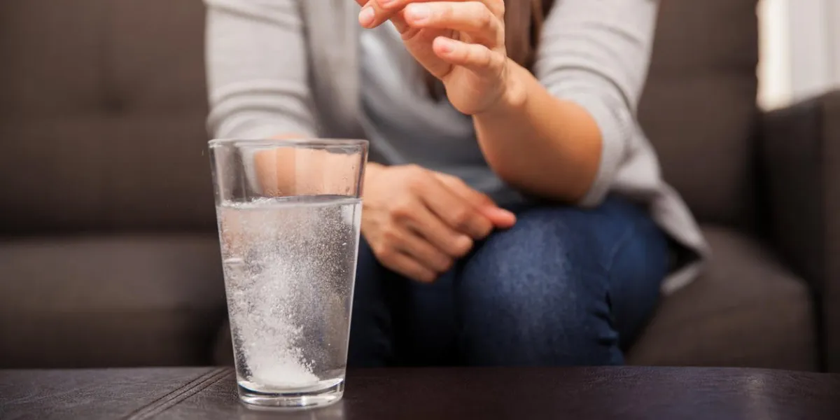 closeup of a young brunette watching an antacid dissolve before drinking