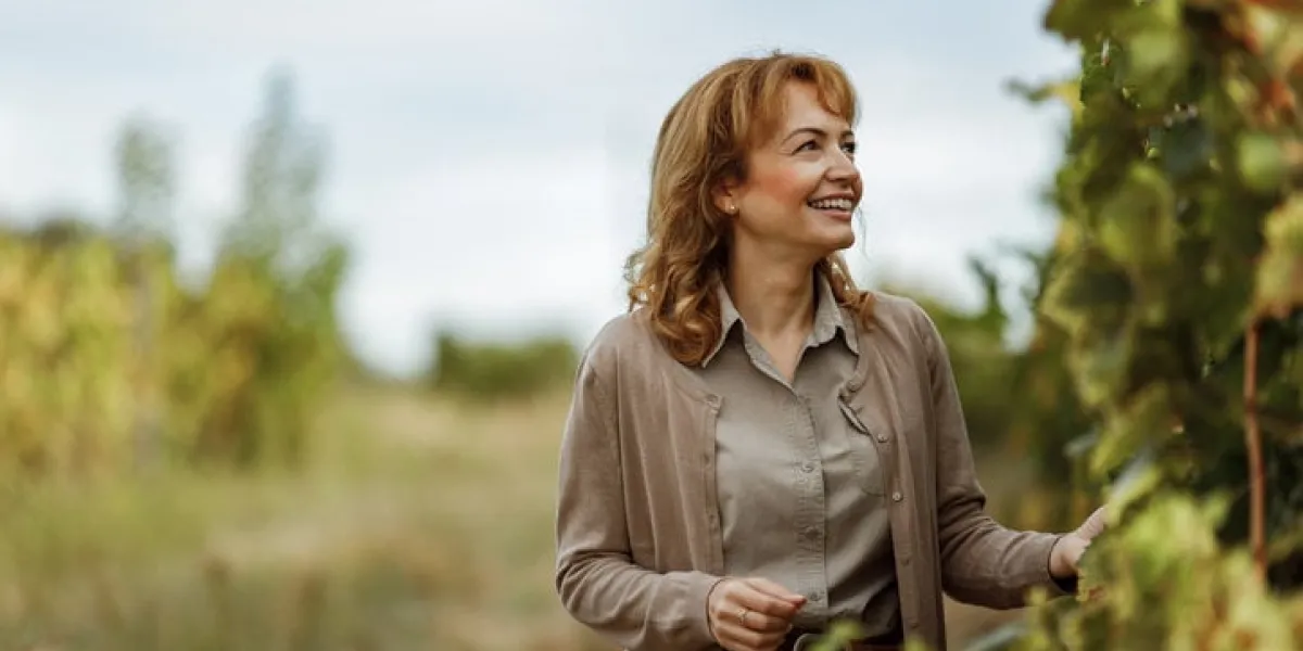 portrait of adult woman, standing next to tree line
