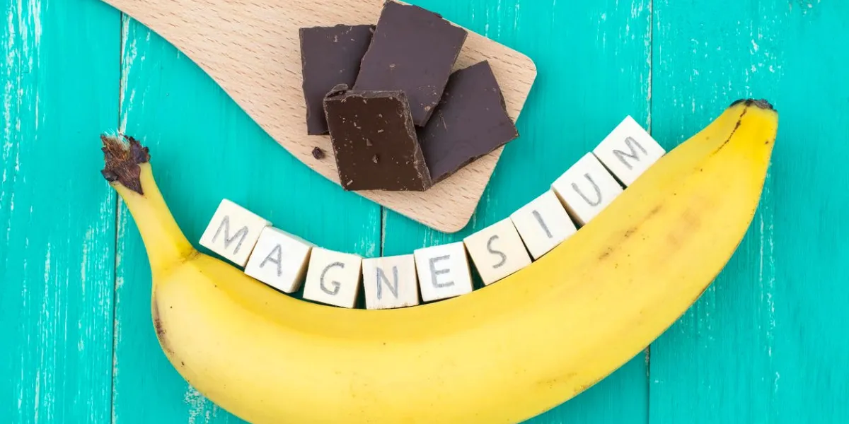 banana, dark chocolate and wooden cubes on an aqua colored table they symbolize rich magnesium food