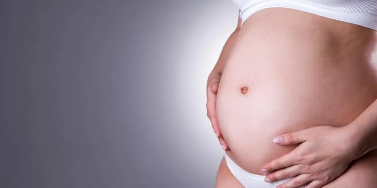 ventre de femme enceinte gros plan sur fond gris avec copie studio