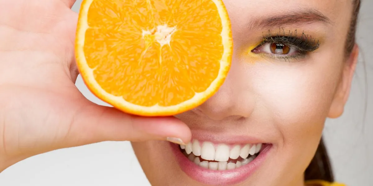 portrait d'une jolie jeune femme tenant une tranche d'orange devant son visage