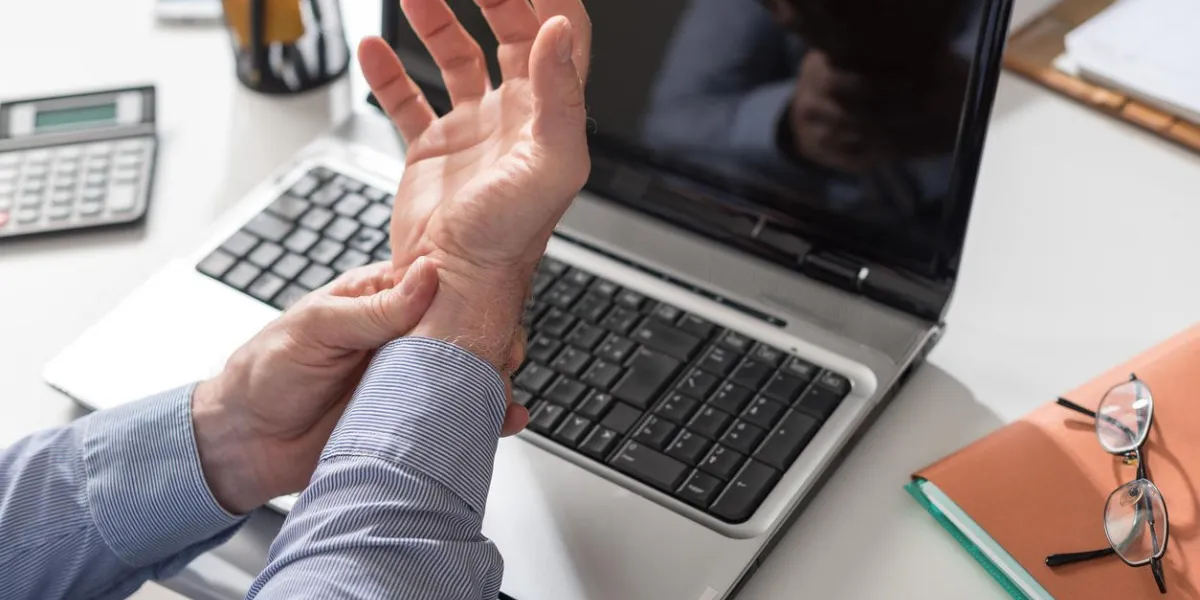 businessman suffering from wrist pain in office