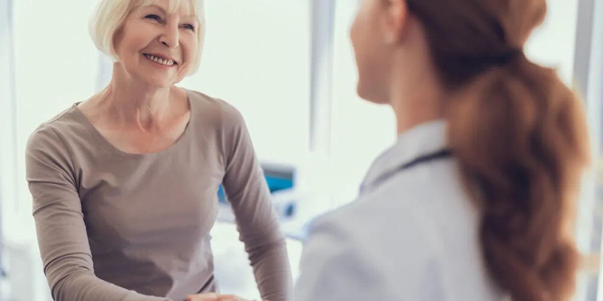 focus on smiling lady shaking hands with physician after visit to clinic she is feeling very grateful for receiving medical treatment copy space in right side