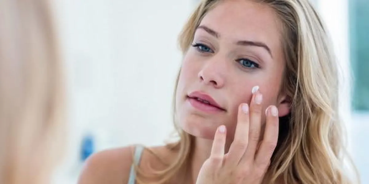 jolie femme souriante, appliquer la crème sur son visage