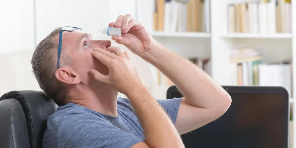 man applying eye drops after a long sitting at computer
