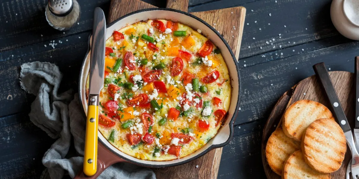 vegetable frittata in a cast iron skillet on wooden background delicious brunch, top view