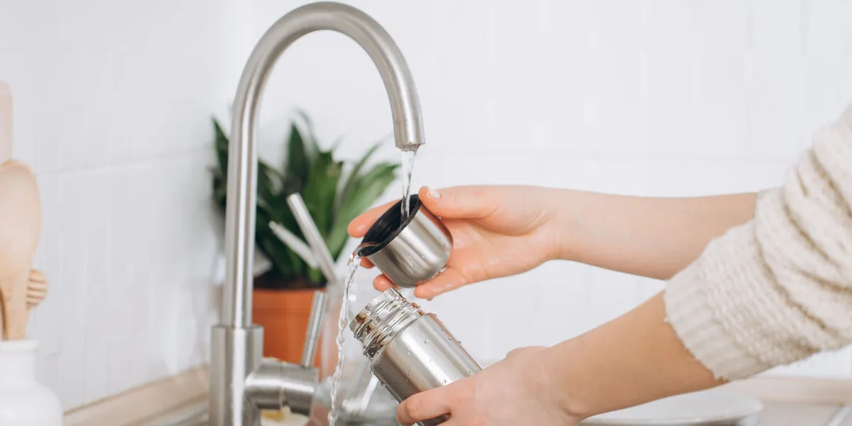 woman washes a metal reusable bottle with an eco-brush zero wa
