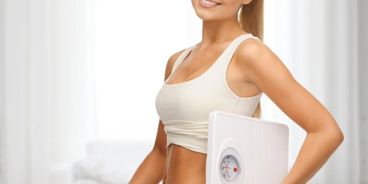 concept de remise en forme, alimentation et soins de santé - femme sportive montrant de grands pantalons et tenant des échelles