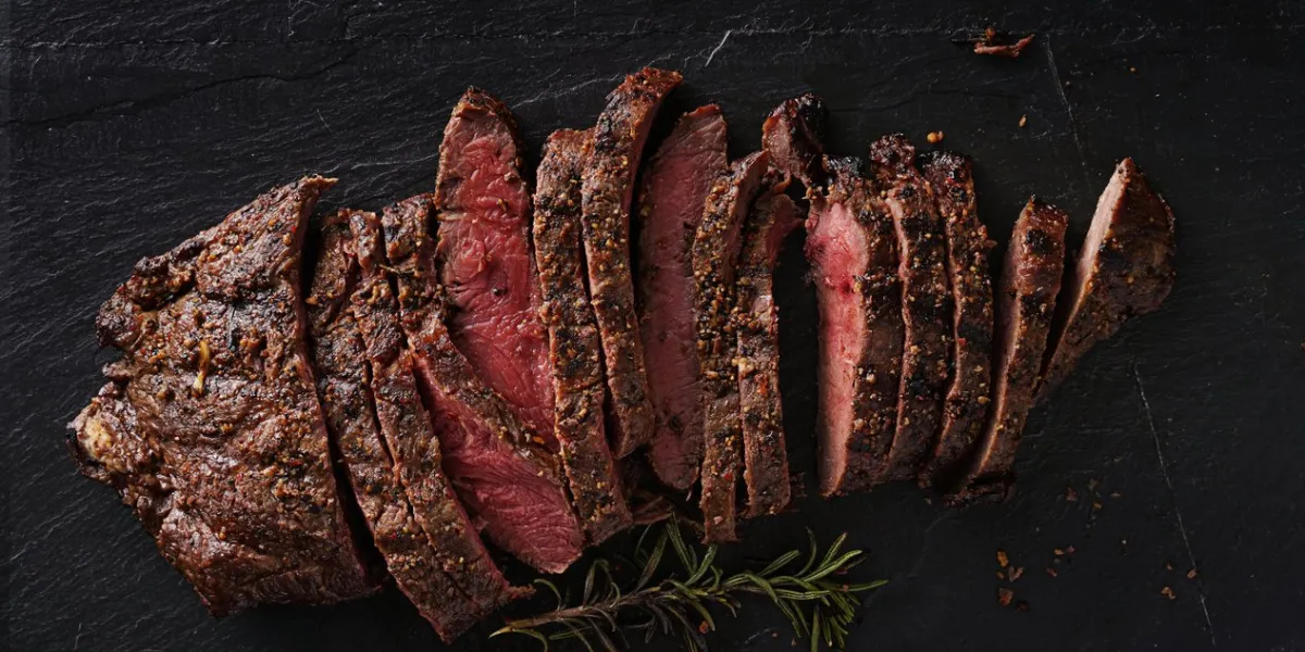 grilled flat iron steak shot in flat lay style from overhead on dark slate