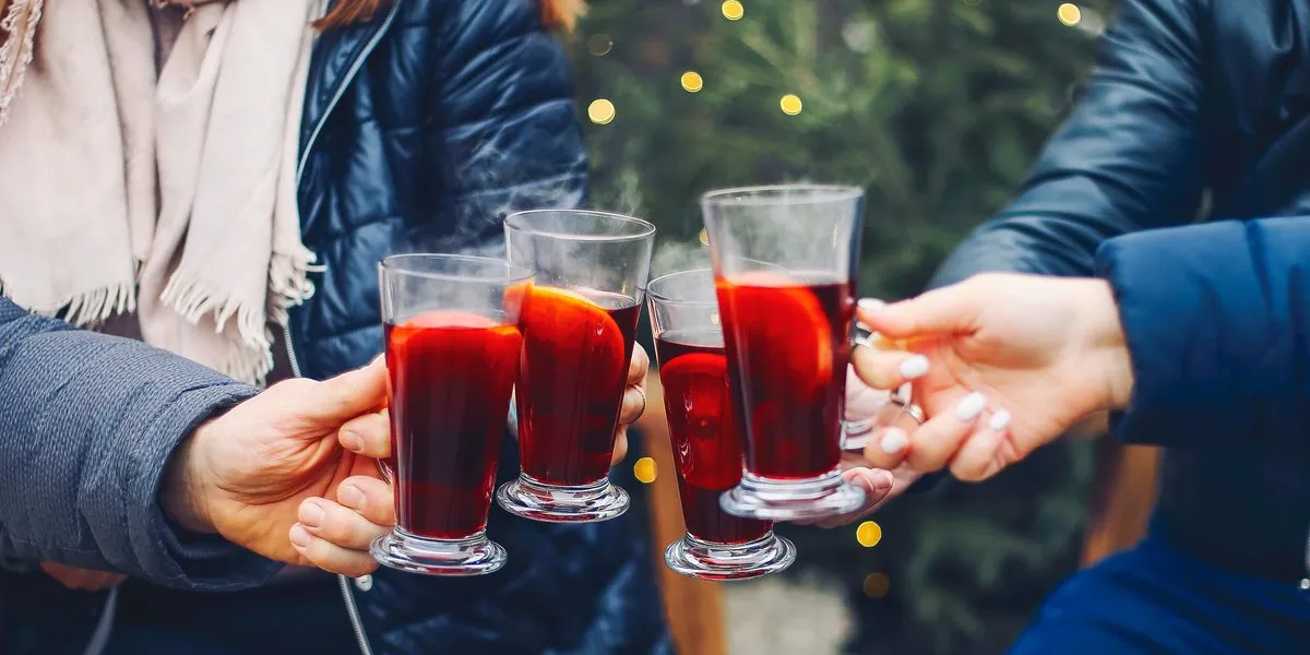 friends drinking delicious mulled wine at party shot of a group of cheerful young friends having fun and enjoying hot drink on the christmas market at an evening party close up