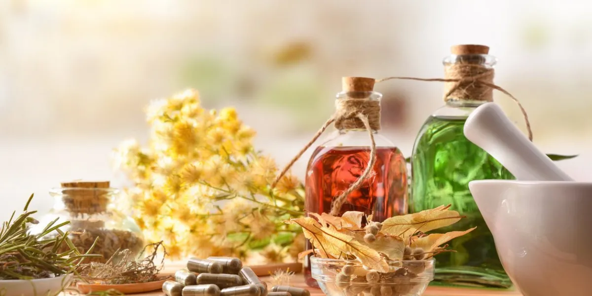capsules and bottles of essence of natural medicine with medicinal plants on wooden table in rustic kitchen front view horizontal composition