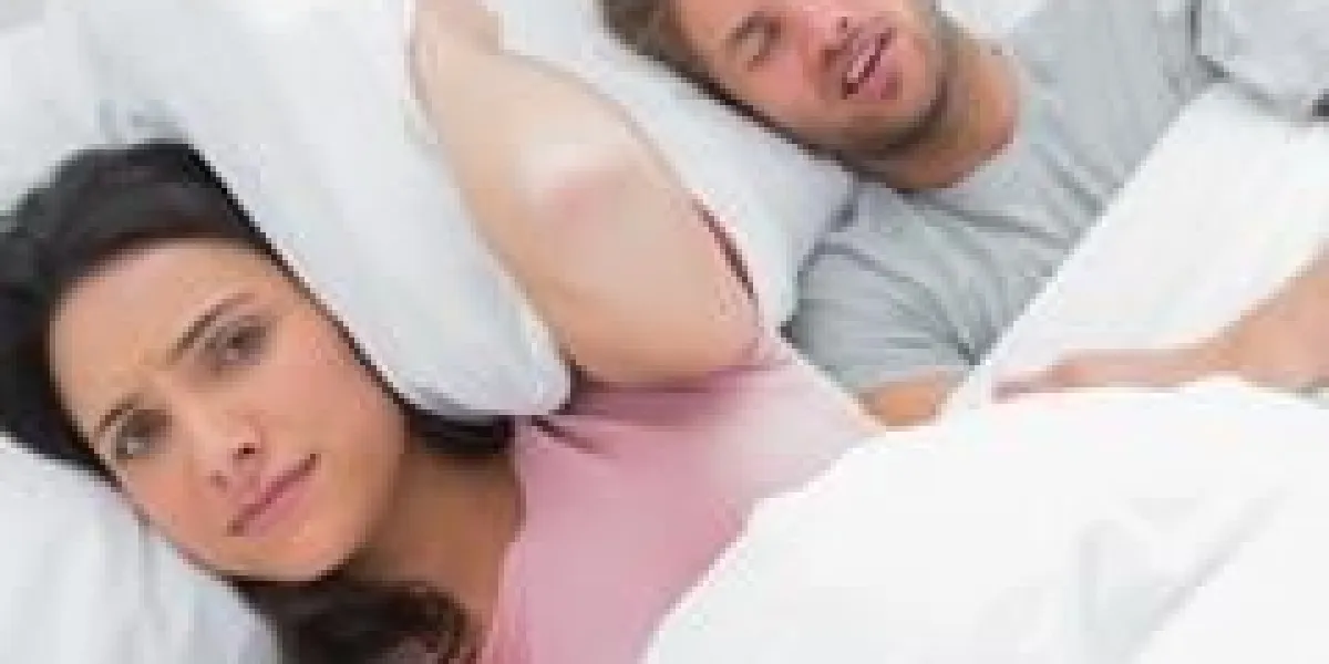 femme bouleversée couvrant les oreilles avec oreiller à côté du mari ronfler à côté d'elle