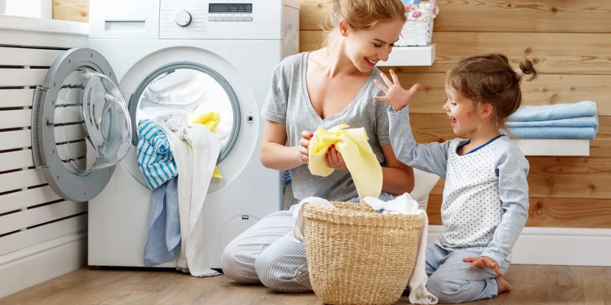 happy family mother housewife and child daughter in laundry with washing machine