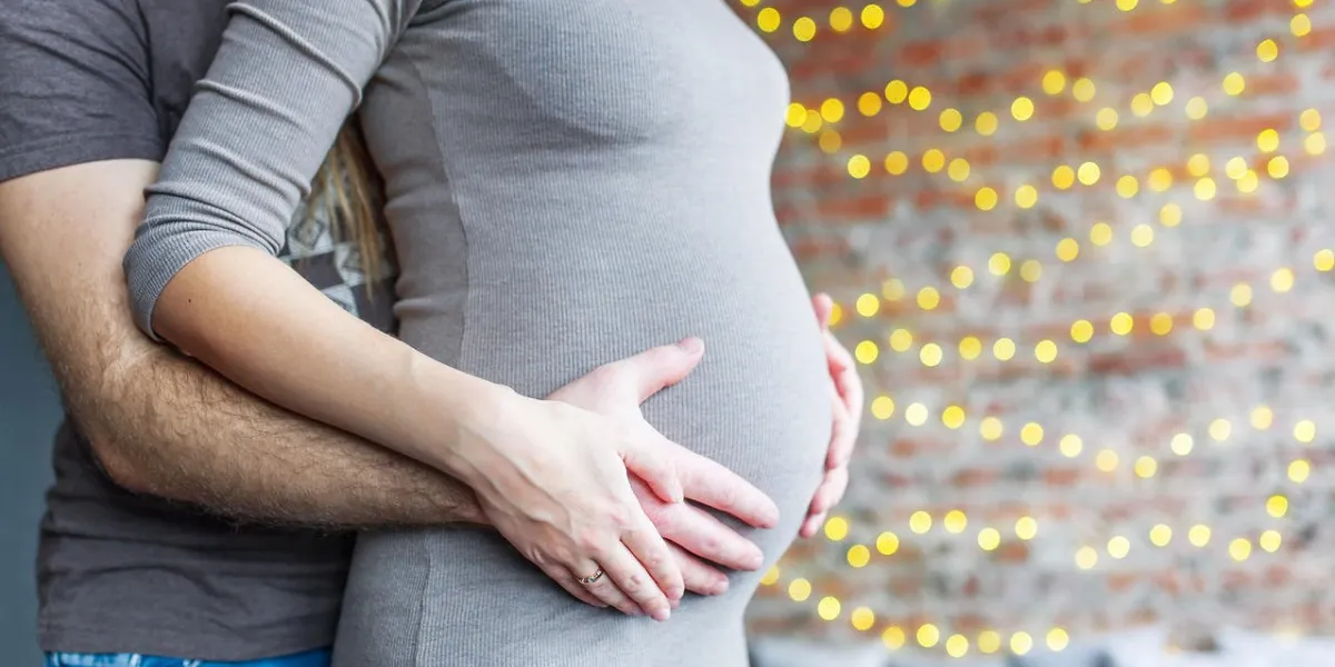 maman et papa avec les mains sur le bébé, sur le fond d'un mur de briques avec un gros plan de guirlande