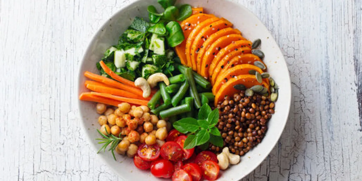 healthy vegetarian salad lentil, chickpea, carrot, pumpkin, tomatoes, cucumber wooden background top view