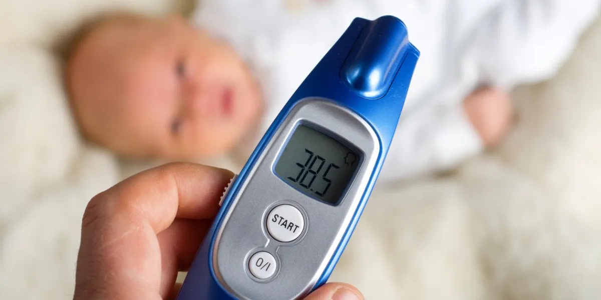 mom checks the temperature of ill baby with blue termomether