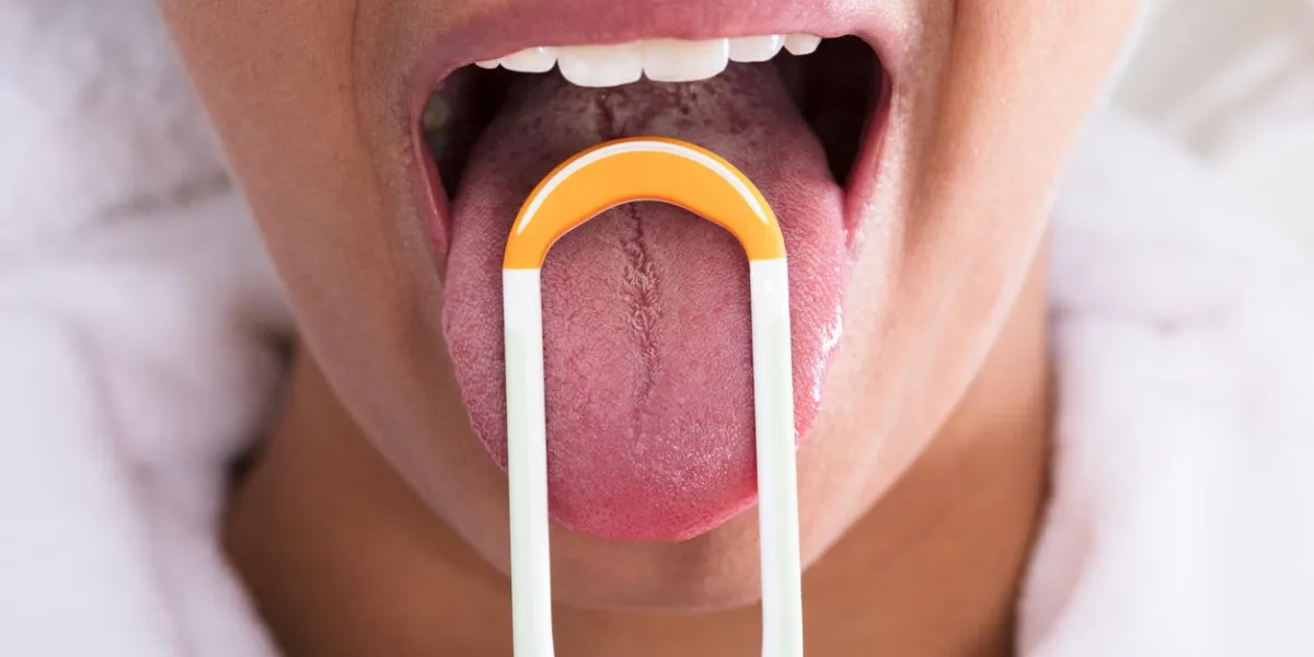photo of young woman cleaning tongue with cleaner