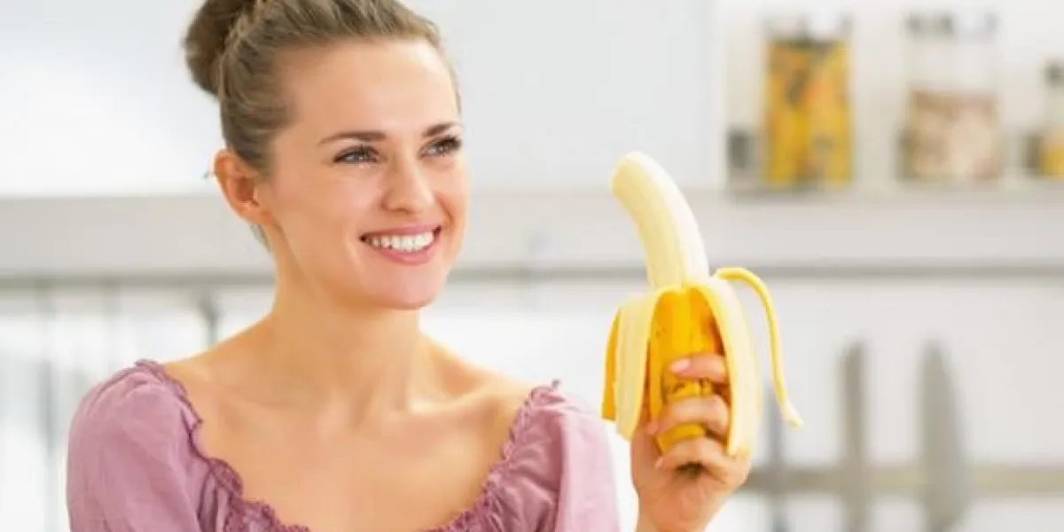 heureuse jeune femme mangeant des bananes dans la cuisine