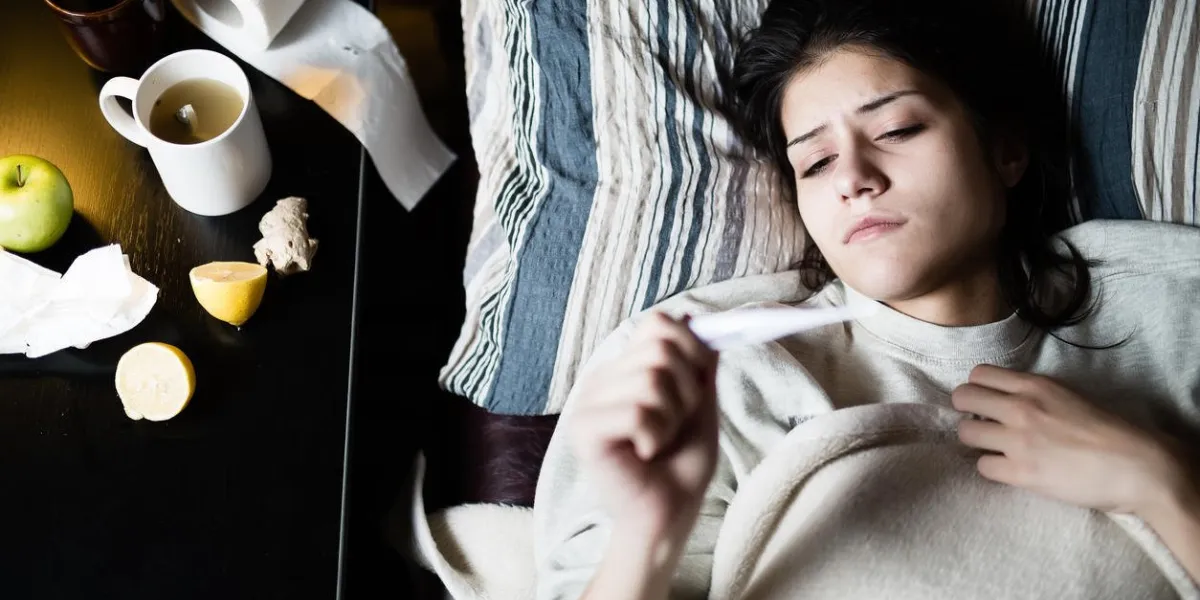 femme malade au lit, appel malade, jour de congé du travail thermomètre pour vérifier la température pour fevervitamins et thé chaud en face de la grippe femme attrapé femme coldvirussick couché sous la couverture de laine