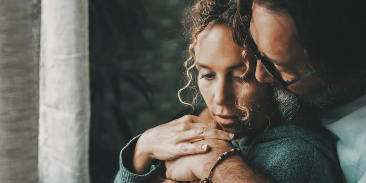 love and relationship with young mature man and woman at home in romantic indoor leisure activity together one adult man hug bonding serene woman in front of a window romance and people embrace