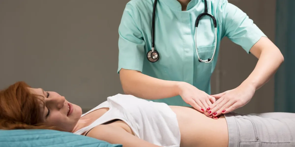 coup d'une jeune femme ayant son estomac examiné par un médecin