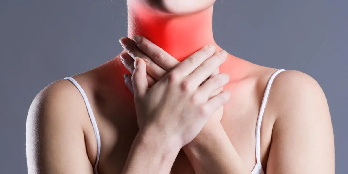 sore throat, woman with pain in neck, gray background, studio shot